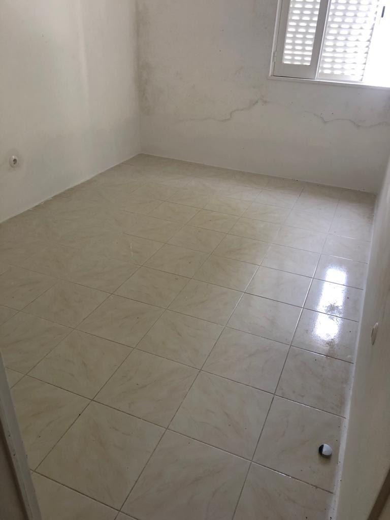 Glazed tiles and grout lines on a bathroom floor before microcement