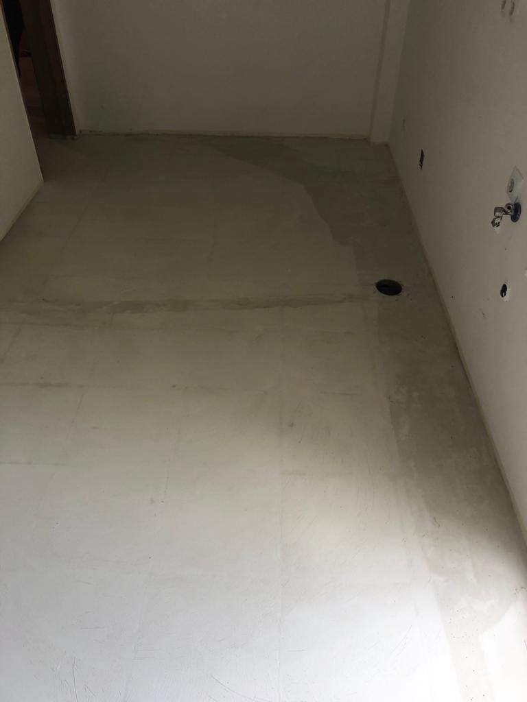 Microcement base coat applied over the existing bathroom floor tiles