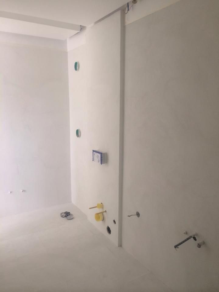 Bathroom wall finished in seamless microcement with no tile lines or grout