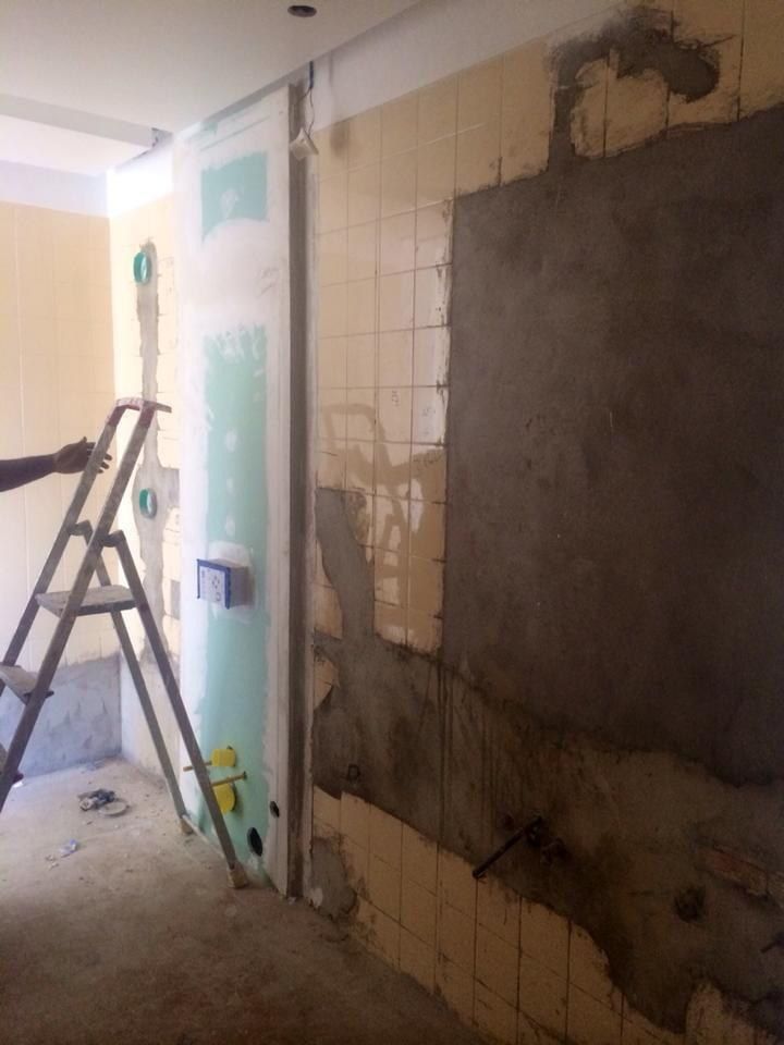 Bathroom wall with old tiling stripped back and patched plaster before microcement