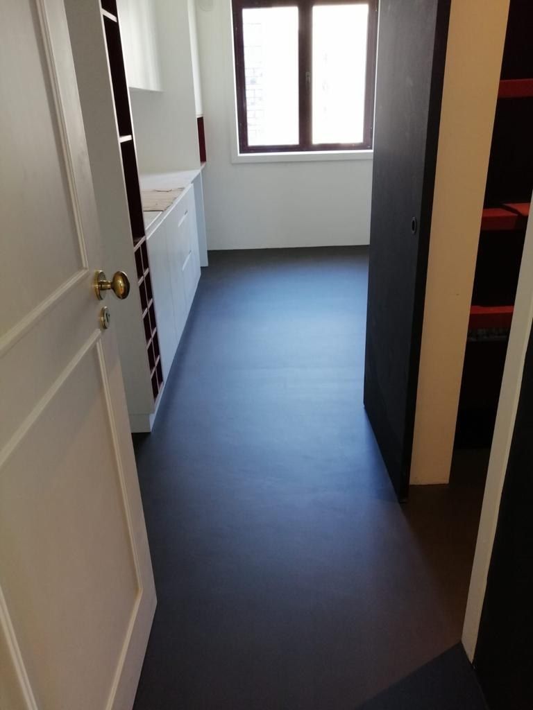Finished seamless dark microcement hallway floor running through the doorway