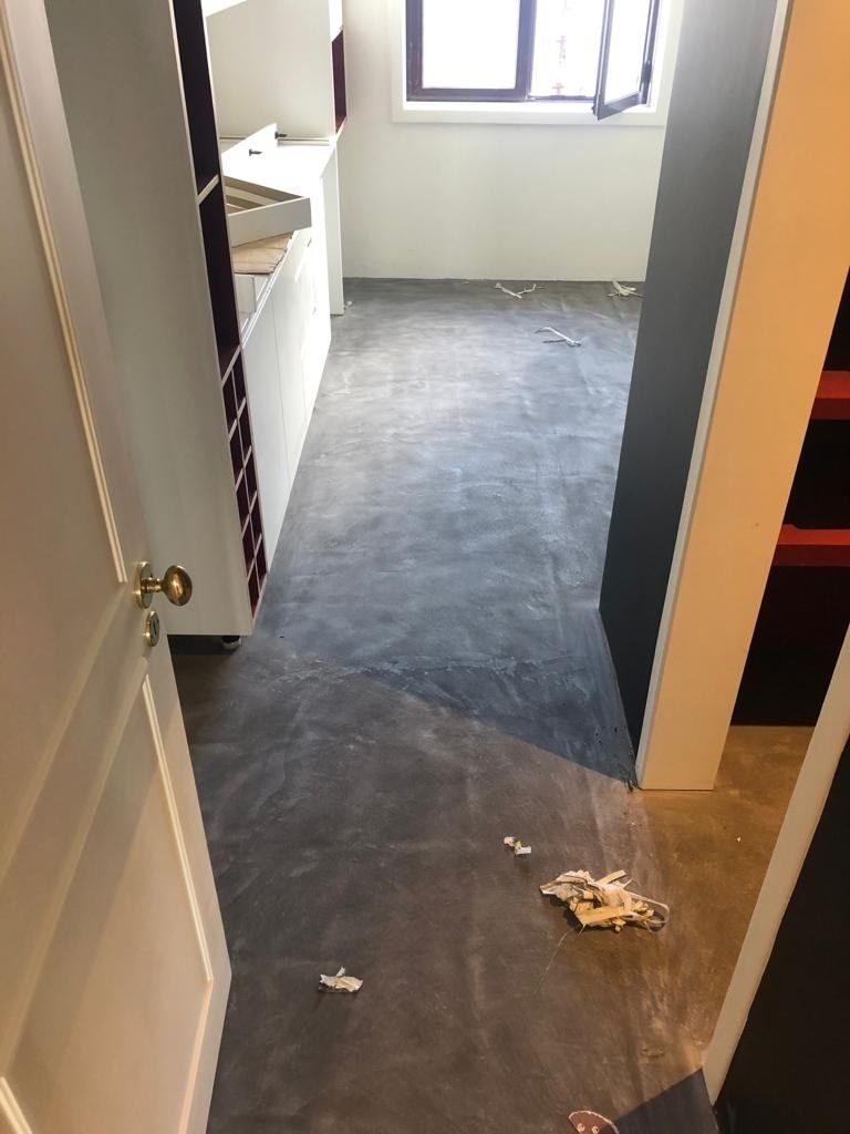 Microcement base coat being worked over the existing hallway tiles