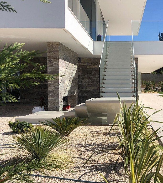 Exterior cantilevered staircase finished in pale microcement with a glass balustrade