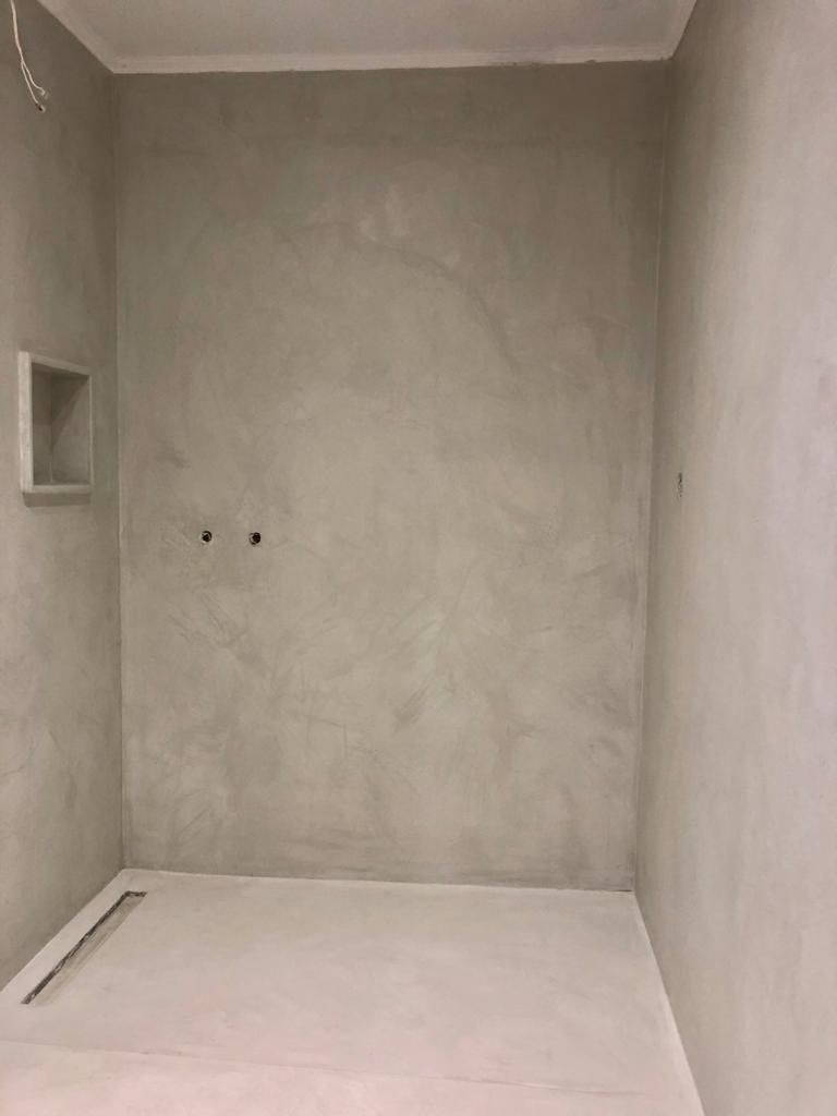 Finished wet room with seamless microcement walls, niche and floor and a flush linear drain