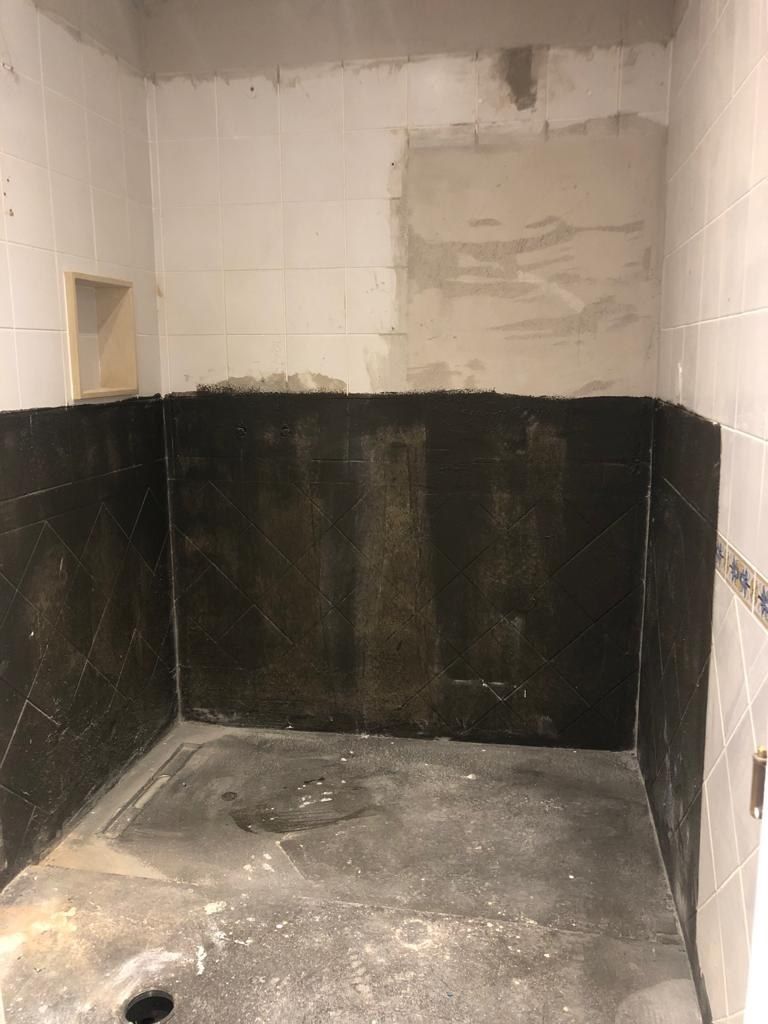 Dark tiled shower enclosure before microcement was applied